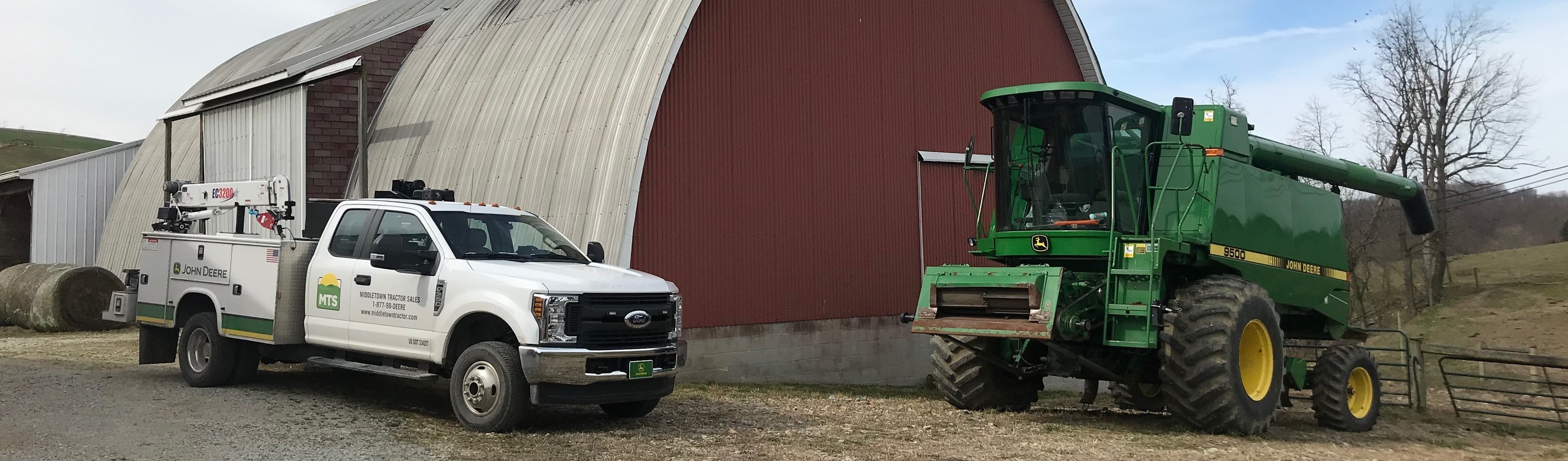 A green and yellow 2018 John Deere tractor sitting in an open grass field